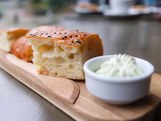 Fette di focaccia su un tagliere, accanto a una ciotolina di formaggio fresco