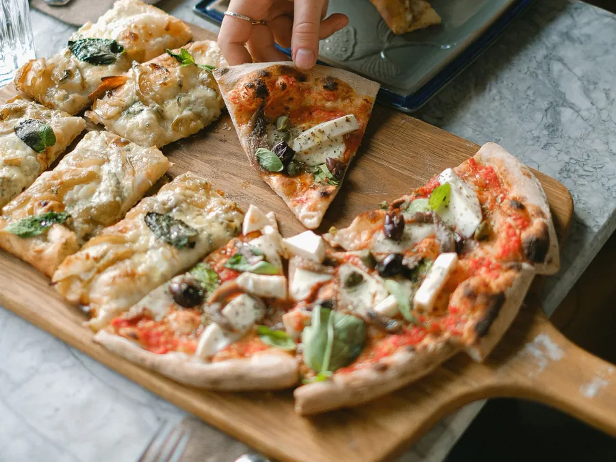 Una pizza lunga tagliata a fette su un tagliere di legno